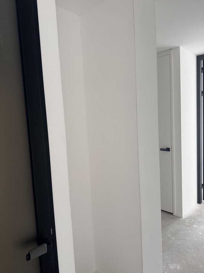 Strakke afwerking van de wand bij een witte binnendeur