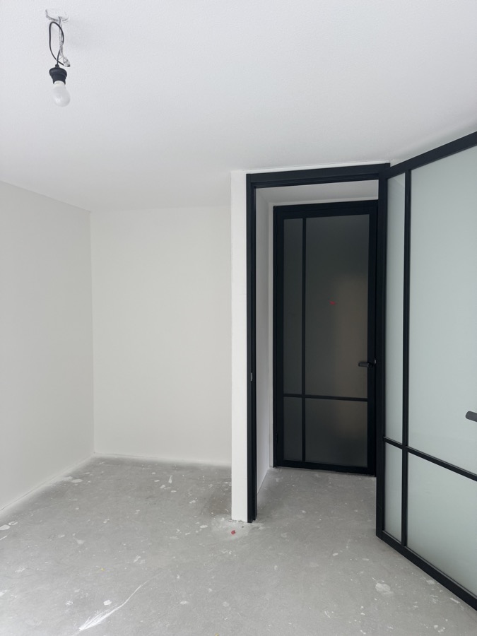 Strak afgewerkte wand rondom zwarte glazen binnendeuren